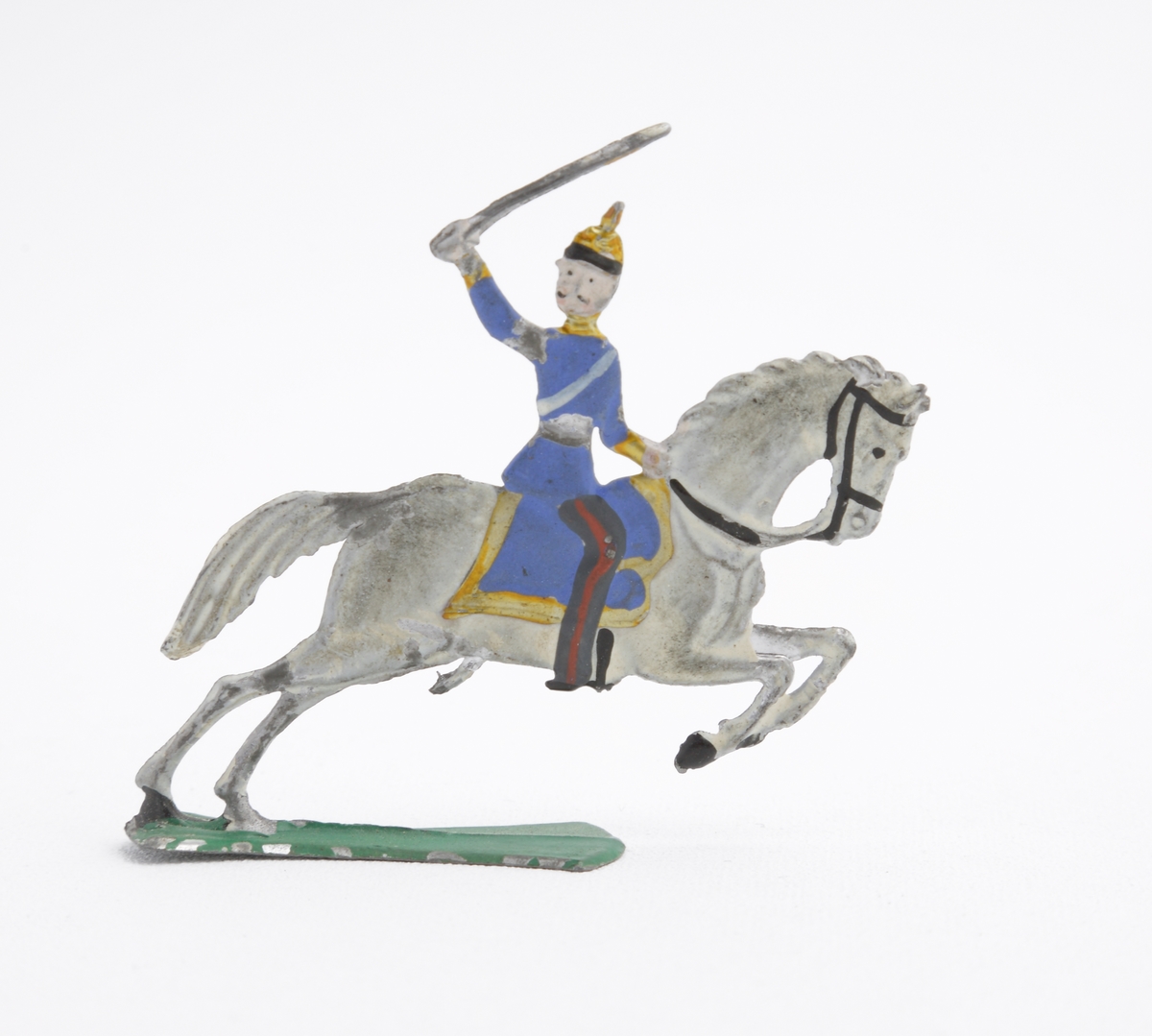 Ryttare till häst i blå uniform med dragen sabel. Han är även utrustad med koppel och pickelhuva. Sadeln är blå med guldfärgade kanter. Hästen vit på grön platta.
Inskrivet i huvudkatalog 1963.