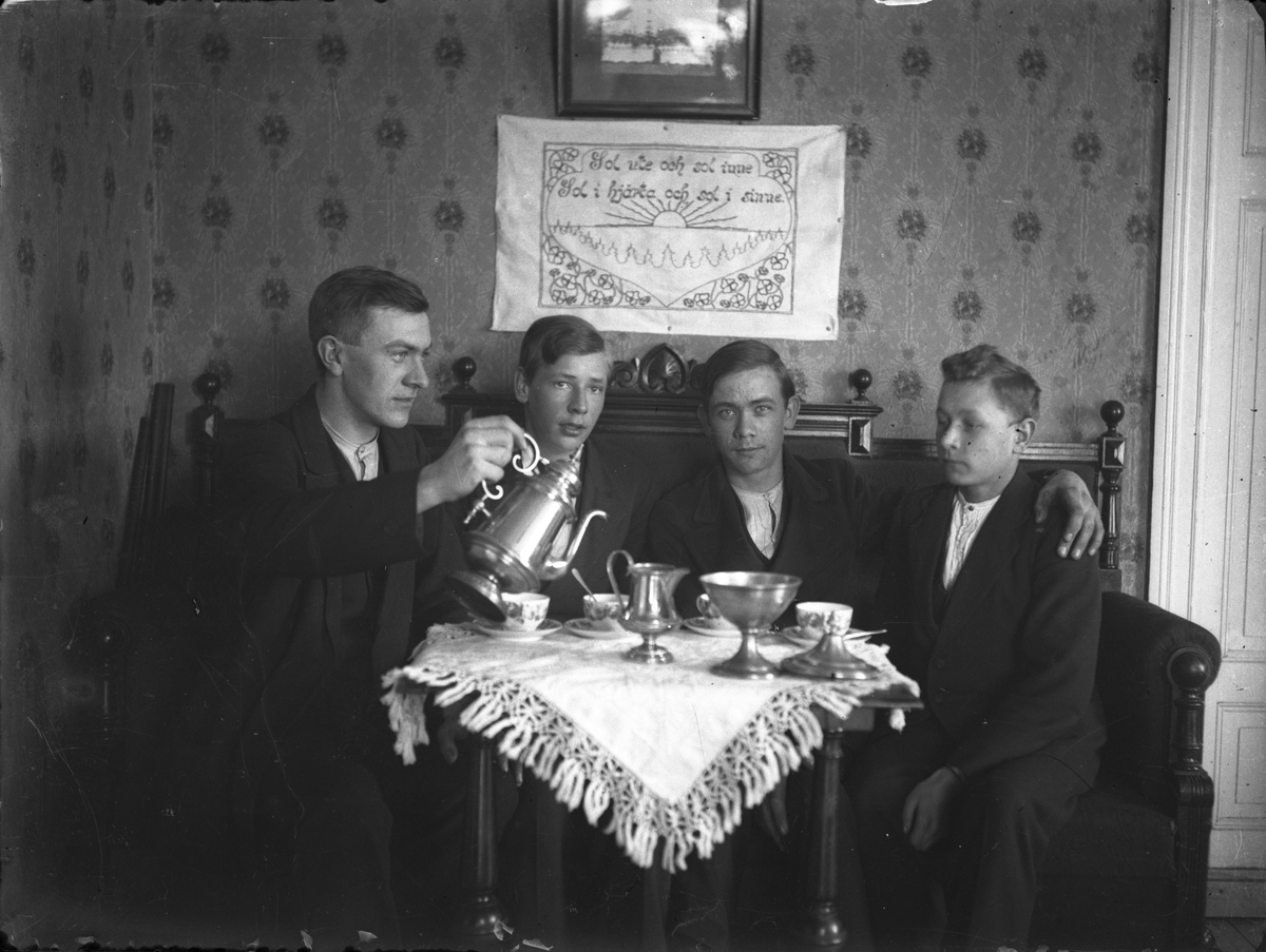 Fyra unga män runt ett kaffebord.