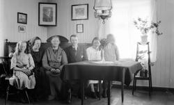 Tre kvinner, en mann og to jenter sitter ved bord.