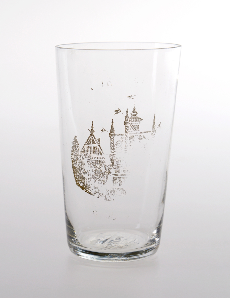 Konisk formet souvenirglass med trykt gullmotiv. Motivet er delvis slitt.