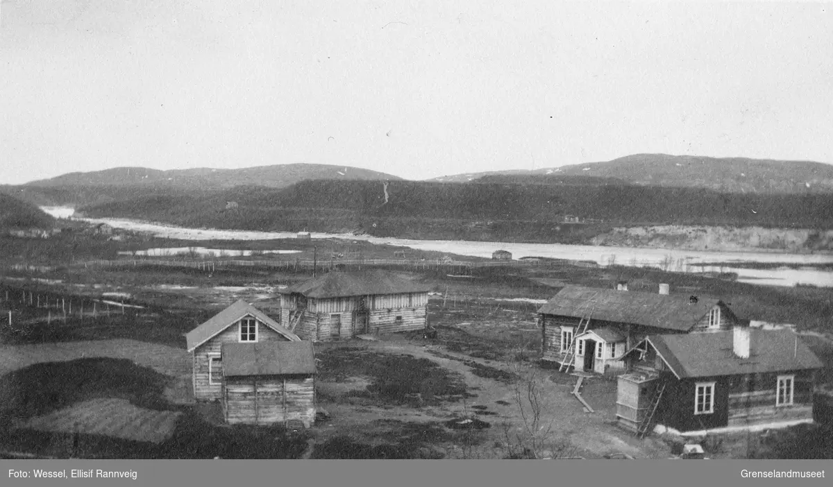 Handelsmann A. Wartiainens gård i Neiden, 1905. I bakgrunnen ses St. Georgs kapell og skoltebyen med skoltesamenes boplass ved fossen.