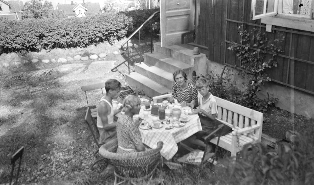 Kvinner og barn spiser et måltid i hagen utenfor enebolig på Hvitsten i 1941.