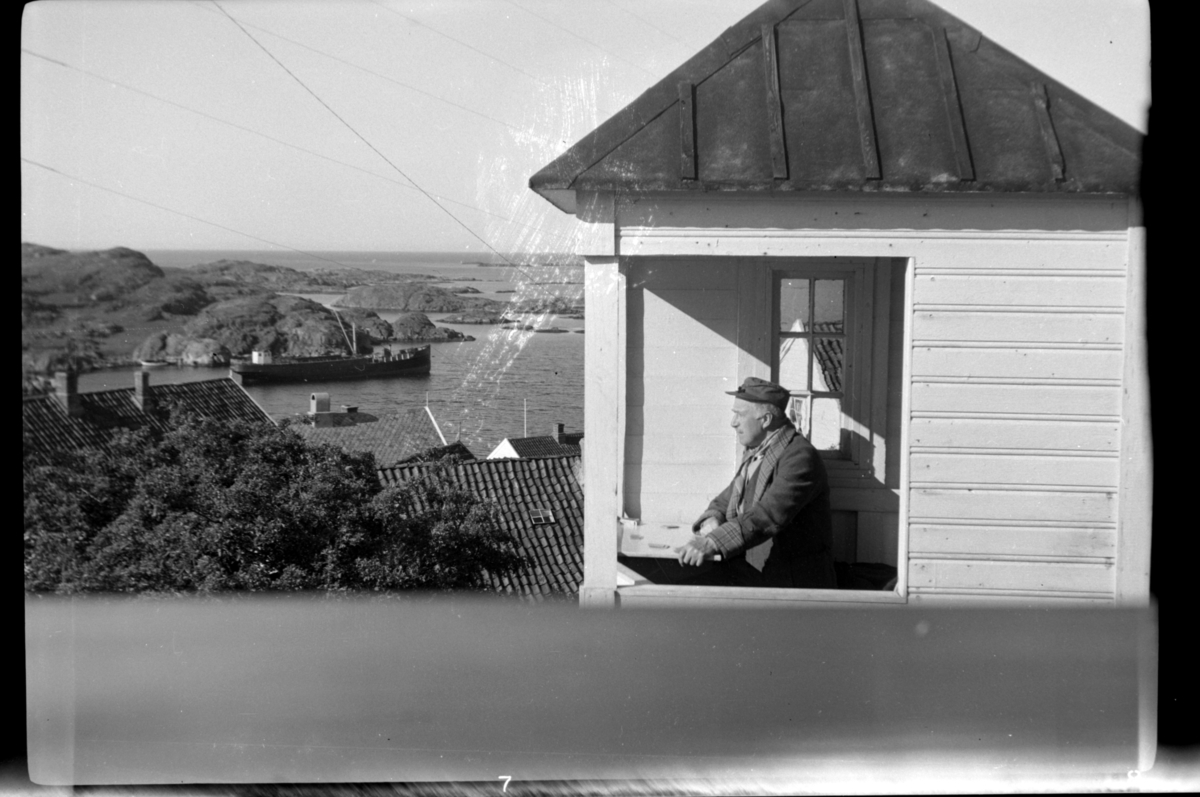 Rolf Sundt sr. sitter i lysthuset, en skøyte ligger fortøyd, Loshavn. Fotografert mai 1953.