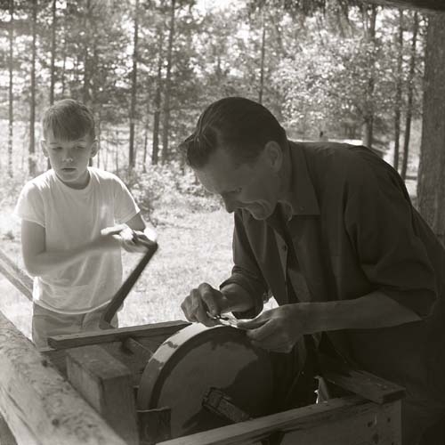 Hilding slipar ett redskap och en pojke drar slipsten åt honom 7 juni 1965.