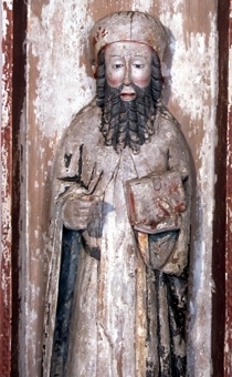 Skulpturen föreställer en mansfigur som håller en bok i sin vänstra hand och ett attribut i höger hand. Han bär en huvudbonad, ett kläde med band i midjan och en mantel. Huvudbonaden är i en klar röd färg, ev två skikt, kanten är förgylld. Hår och skägg är målat i en gråsvart färg. Klädnaden är vit med inslag av rött längs kanterna. Manteln är svart med ett schablonerat guldmönster, bårder är förgyllda och fodret blått. Karnationen har röda kanter och lågt sittande kindrosor. 

Skulpturen står i ett skåp men de två enheterna har separerats. Skulpturen är skuren i ett ljust lövträ och baksidan är grunt urholkad med rak yxa. Höger hand är intappad. Skåpets sidor är något vinklade och fästa mot bakstycket med hjälp av naror. I överkant mot bakstycket och sidornas insida och utsida ligger en mörkröd färg. Tre smidda spikar som tjänat som infästning av skulpturen sitter kvar i skåpets bakstycke.