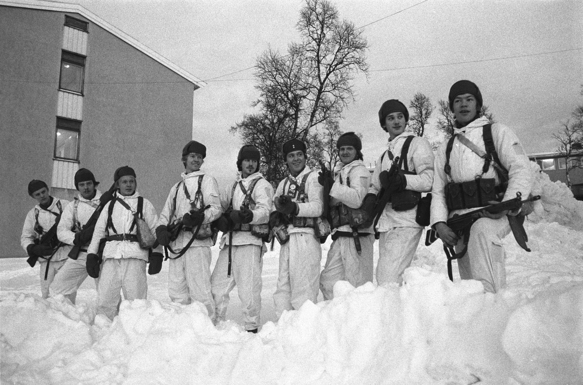 Soldater i vinterkamuflasje. Bygning i bakgrunnen.