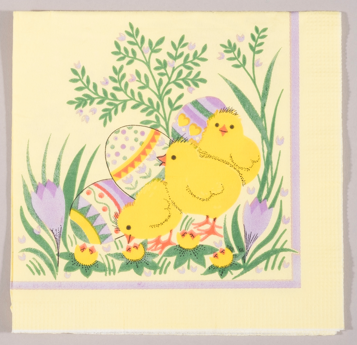 Tre kyllinger og tre store dekorerte påskeegg. Krokus og gule og lilla vårblomster.
