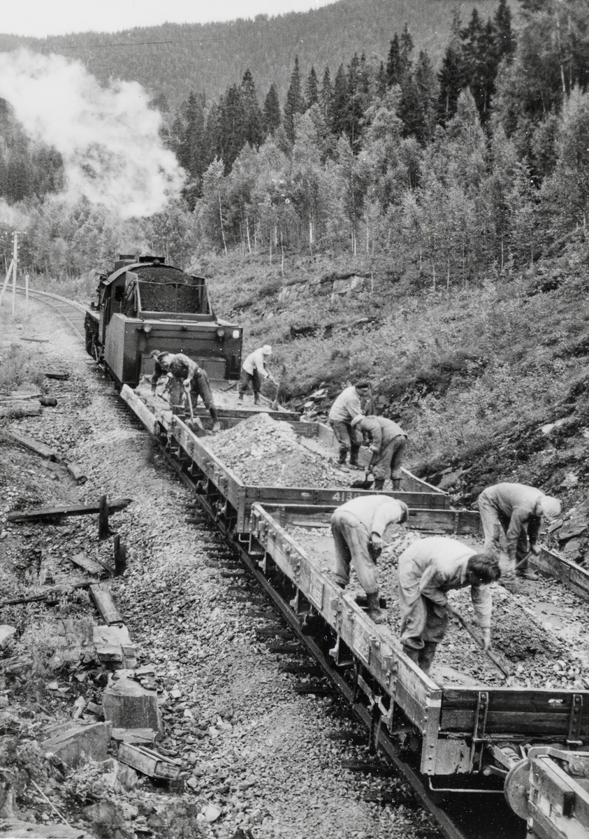 Grustog på Nordlandsbanen trukket av damplokomotiv type 63a nr. 2343. Grusen er hentet fra Spølrem grustak mellom Laksfors og Eiterstraum stasjoner på Nordlandsbanen.  Grusen losses med håndmakt.