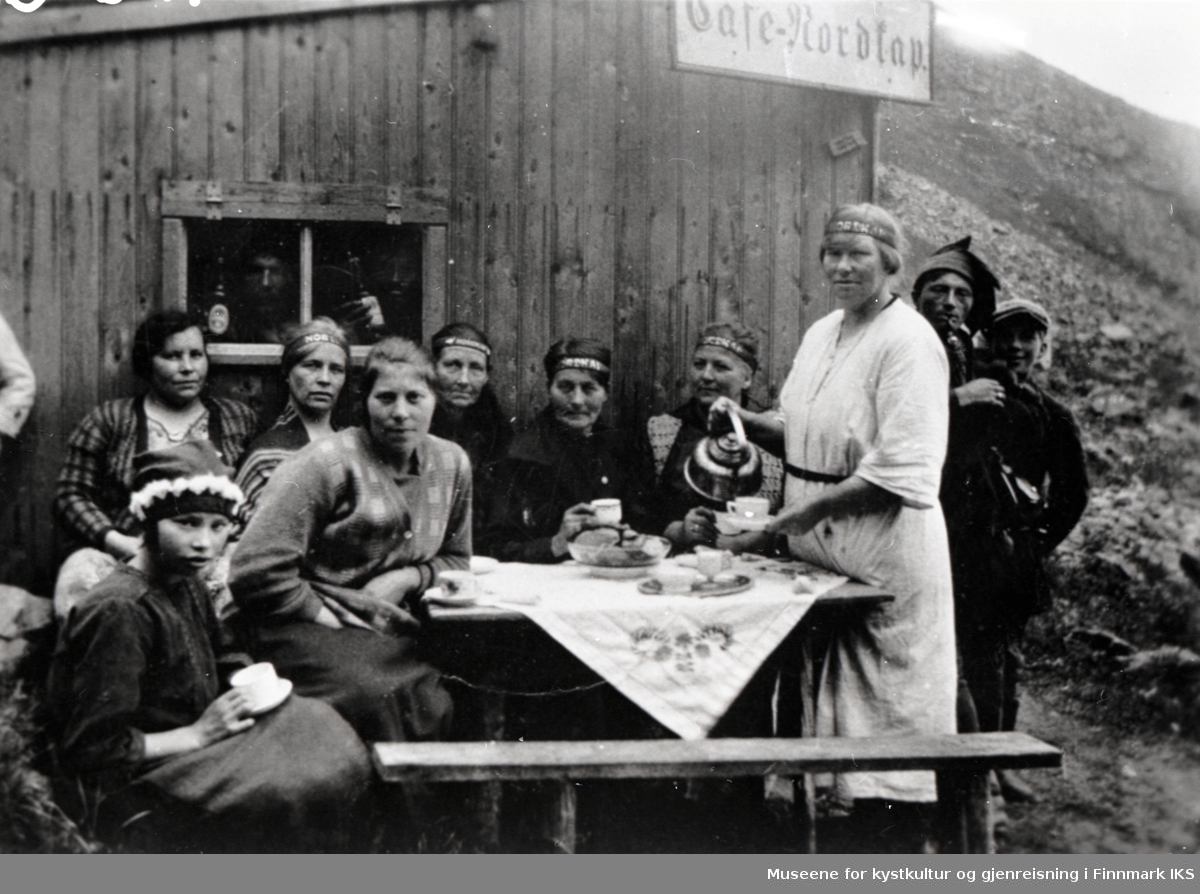 Utenfor 'Café Nordkap', antakelig Severine kafé ovenfor Hornvika. Severine skjenker kaffe til lokal kvinner og menn. 1930-tallet.