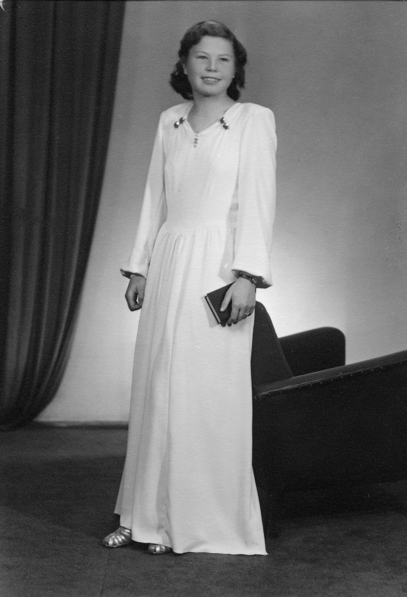 Ung kvinne i lang hvit kjole.