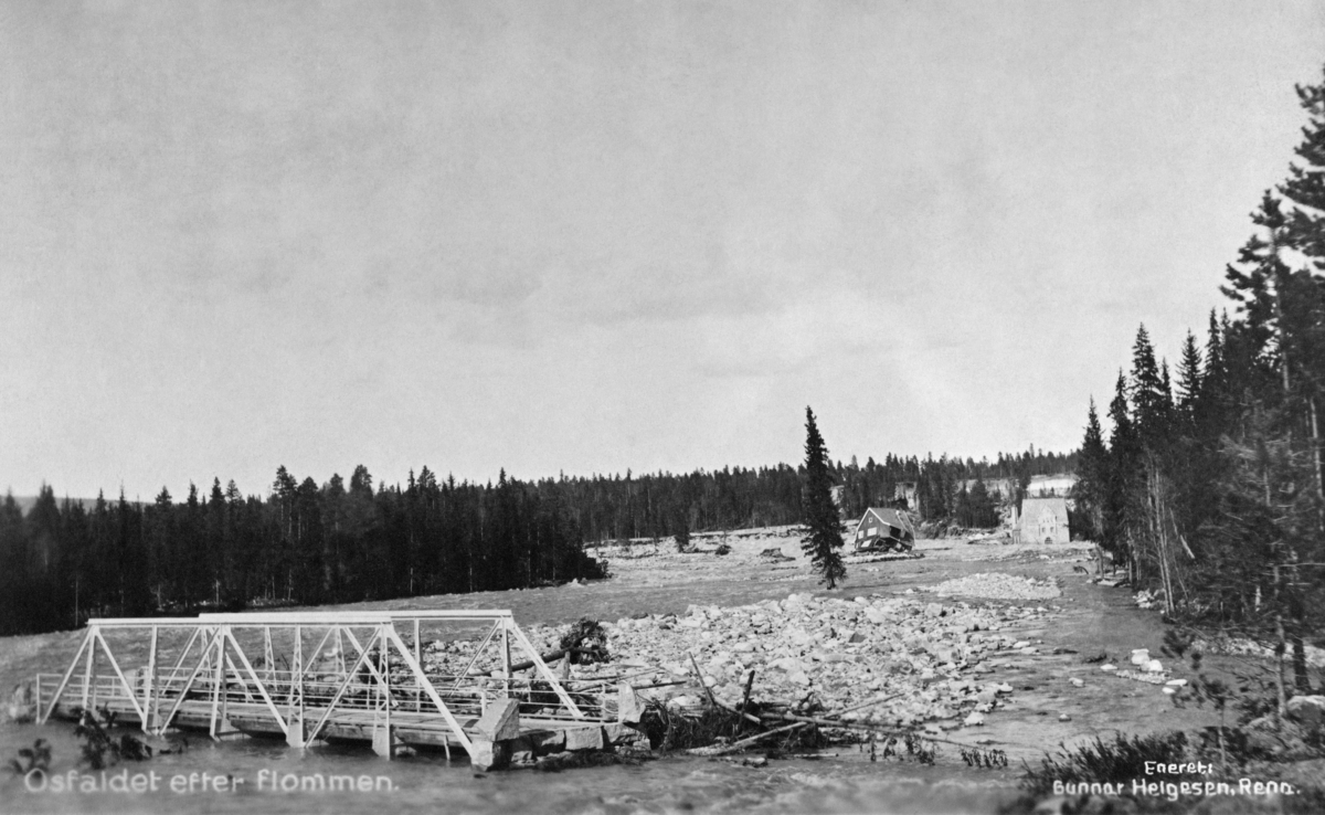 Strandet bru etter flomkatastrofen som ble utløst av dambruddet ved Osfallet kraftverk i elva Søndre Osa i Åmot kommune i Hedmark 10. mai 1916.  Dette fotografiet er entakelig tatt en av de nærmest påfølgende dagene.  Kraftverket ved Osfallet ble satt i drift i oktober 1914.  I begynnelsen av mai 1916 kom våren brått, med varme og kraftige regnskurer.  Dammen - vannmagasinet til kraftverket - ble fort fylt med vann, og karene som betjente anlegget lyktes ikke med å få åpnet sikkerhetsventilene.  Konsekvensen ble at det begynte å sildre vann over nordre damarm.  Vannet grov seg et stadig djupere far, og etter hvert fosset det ut.  Den kraftige strømmen rev med seg trær, sand, grus og steiner, og grov på denne måten et nytt løp nord for det opprinnelige.  Dette løpet gikk rett mot maskinistboligen, som kollapset med to personer i huset, hvorav den ene etter hvert døde.  Også kraftstasjonen ble fylt av sand, grus og stein.  De store vannmassene grov dessuten kraftig på begge sider av elveløpet, og etterlot seg et landskap der markoverflata var dekt av stein.  Flommen rammet også fagverksbrua over vegen mellom Rena i Åmot og Jordet i Trysil (i dag fylkesveg 215, Haugedalsvegen), og den ble liggende ei elva som en demning for stein og trestammer som kom flytende ovenfra.

Mer informasjon om kraftutbygginga ved Osfallet og det påfølgende dambruddet finnes under fanen «Opplysninger».