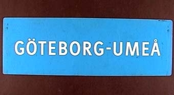 Långsmal dubbelsidig skylt av blå plast med vit text: "GÖTEBORG - UMEÅ"

Text på andra sidan:

"UMEÅ - ÖREBRO - GÖTEBORG"