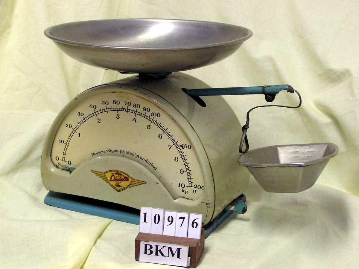 Form: halvsirkel på fot m. vektskål oppå  og en liten sideskål på stang
