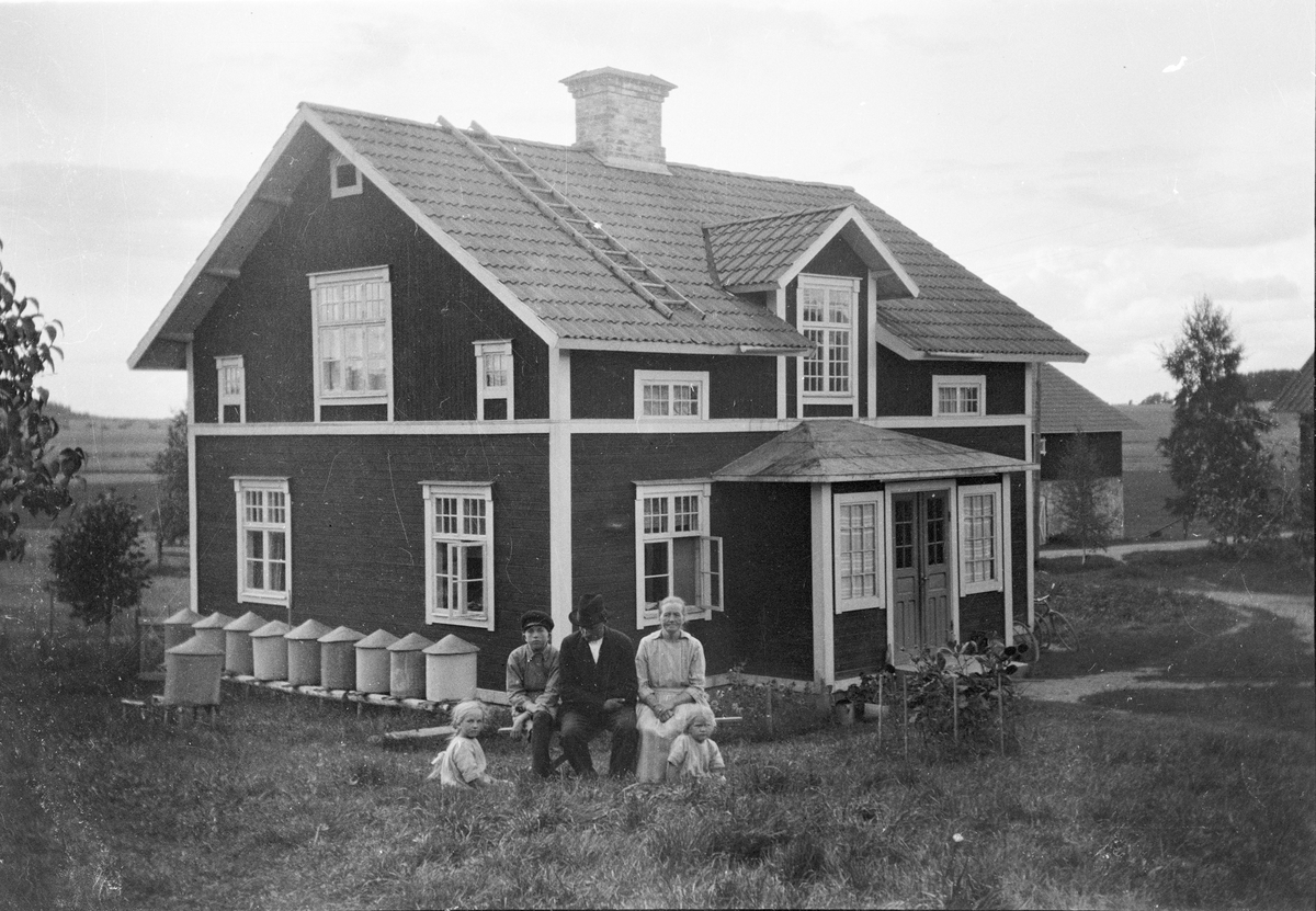 Familj framför bostadshus med bikupor i Sävasta, Altuna socken, Uppland 1925