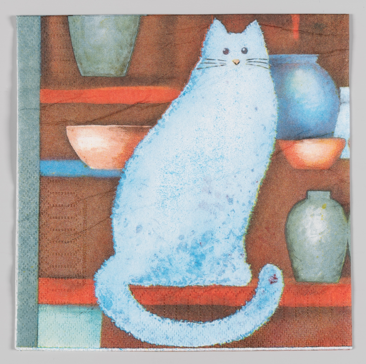 En lysblå katt sitter på en hylle omgitt av boller og krukker.