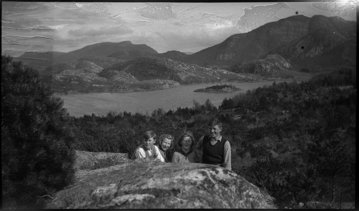 Jon Madland, Harry Nilsen og to jenter på sykkeltur til Lutsi. Det er bilder av barna på fjellet med Lutsivatnet i bakgrunnen . Guttene bytter på å holde et gevær.