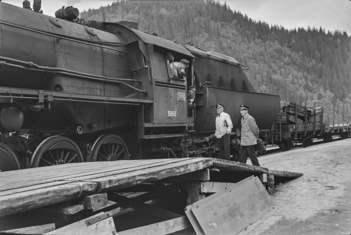 Underveisgodstoget fra Trondheim til Hamar over Røros, tog 5712, har stoppet på Kotsøy stasjon. Lokomotivpersonale og konduktørpersonale konfererer. Toget trekkes av damplokomotiv type 63a nr 5860.