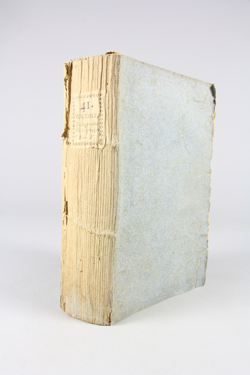 Bok, pappband,"Oeuvres complètes de Voltaire."  del 41, tryckt 1785.
Pärm av gråblått papper, på pärmens insidor klistrade sidor ur annan bok. Med skurna snitt. På ryggen pappersetikett med tryckt text med volymens namn och nummer. Ryggen blekt.