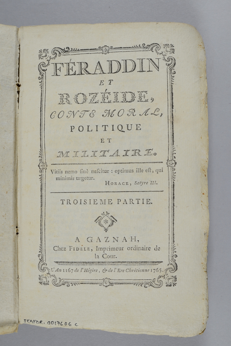 Bok, pappband,"Féraddin et Rozéide, conte morale, politique et militaire", del 3,  tryckt 1765 i Gaznah.
Pärm av gråblått papper, oskuret snitt. På ryggen pappersetikett med volymens namn och nummer. Ryggen blekt.
