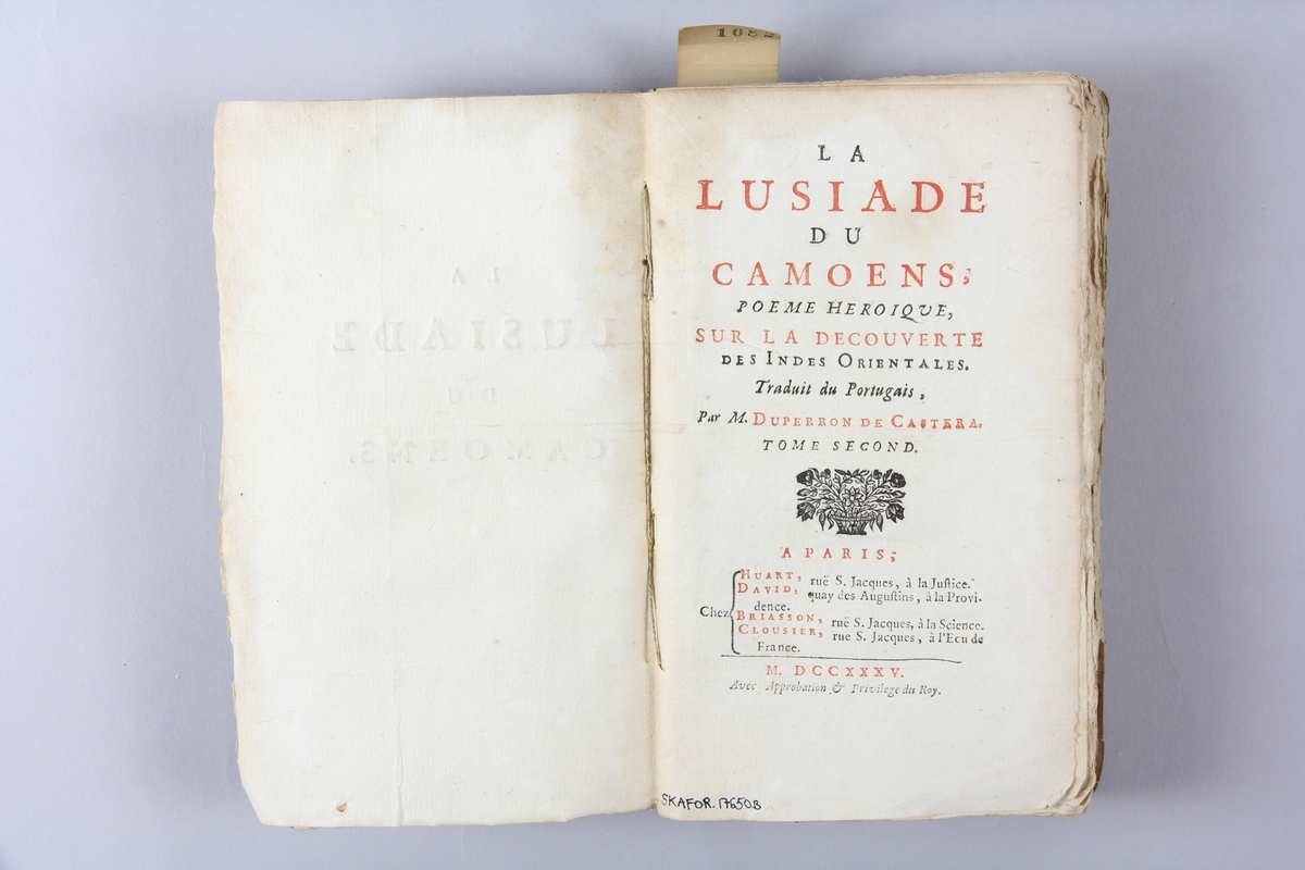 Bok, häftad, "La Lusiade de Camoens", del 2, tryckt 1735 i Paris.
Pärm av marmorerat papper, oskuret snitt.  Blekt rygg med  pappersetikett med volymens titel och samlingsnummer. Illustrationer i koppartryck.