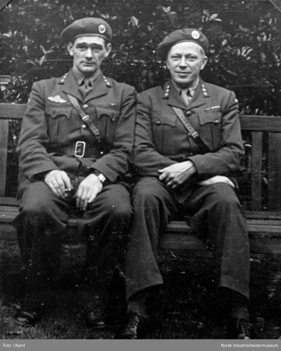 Major Leif Tronstad i London under andre verdenskrig sittende på benk med ukjent selskap. Begge kledd i offisertjeneste uniform med Sam Brown belte.
