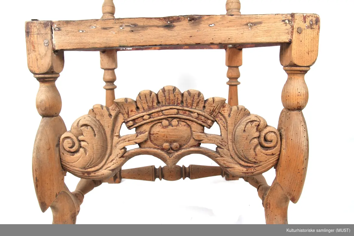 Toppstykke med skjell som minner om rokokkostolens trekk. Dette tyder på at det er en barokkstol med sekundær rygg fra midten av 1700-tallet. Dette er antagelig gjort for å modernenisere stolen og tilpasse den til rokokkostil. 
Bindingsspross med utskjæring i form av krone og akantusblad. 
Løveføtter. Mangler setet.