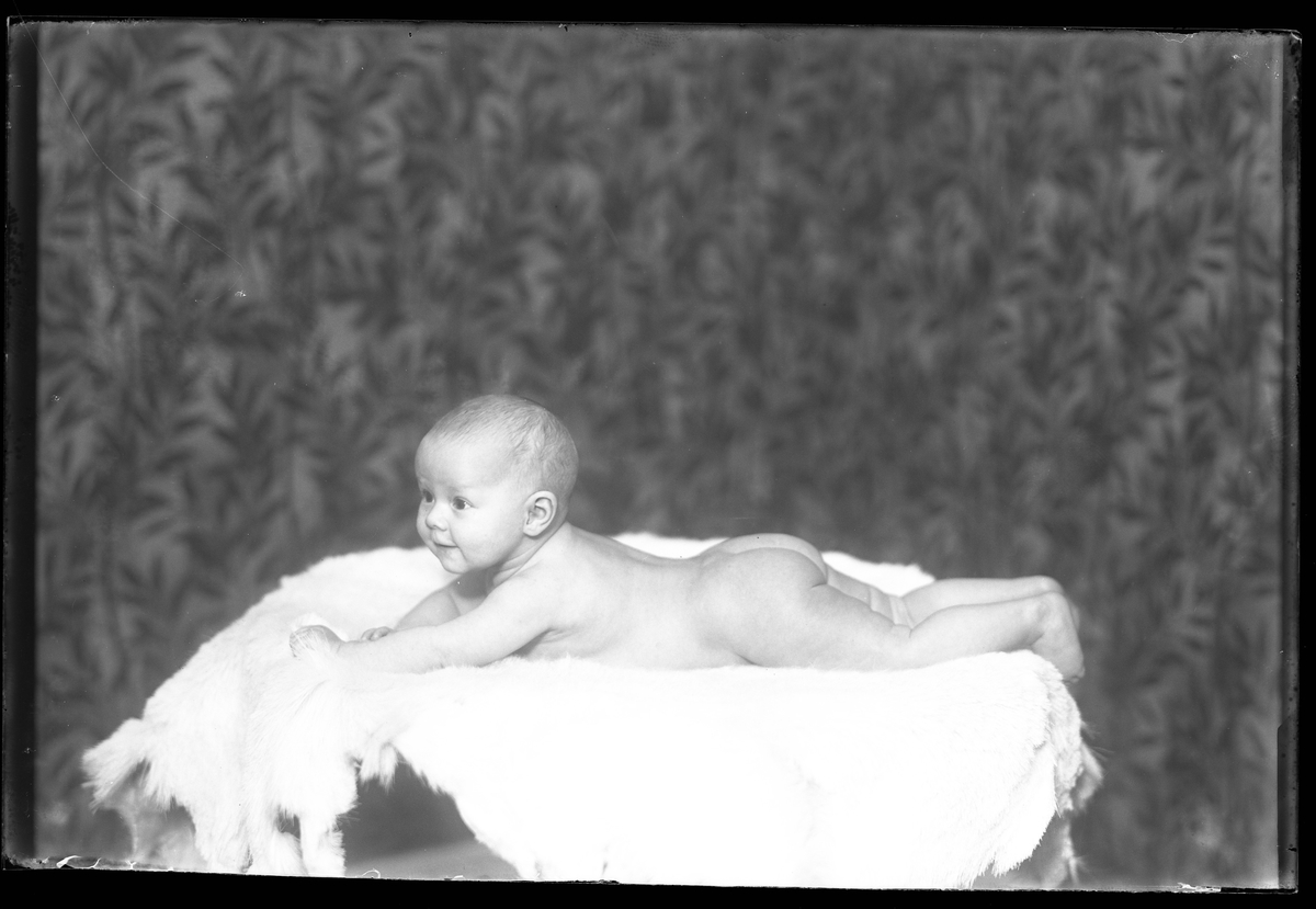 Ett litet barn ligger på en fäll. I fotografens anteckningar står det "Fam. Björn Klinges pojke".