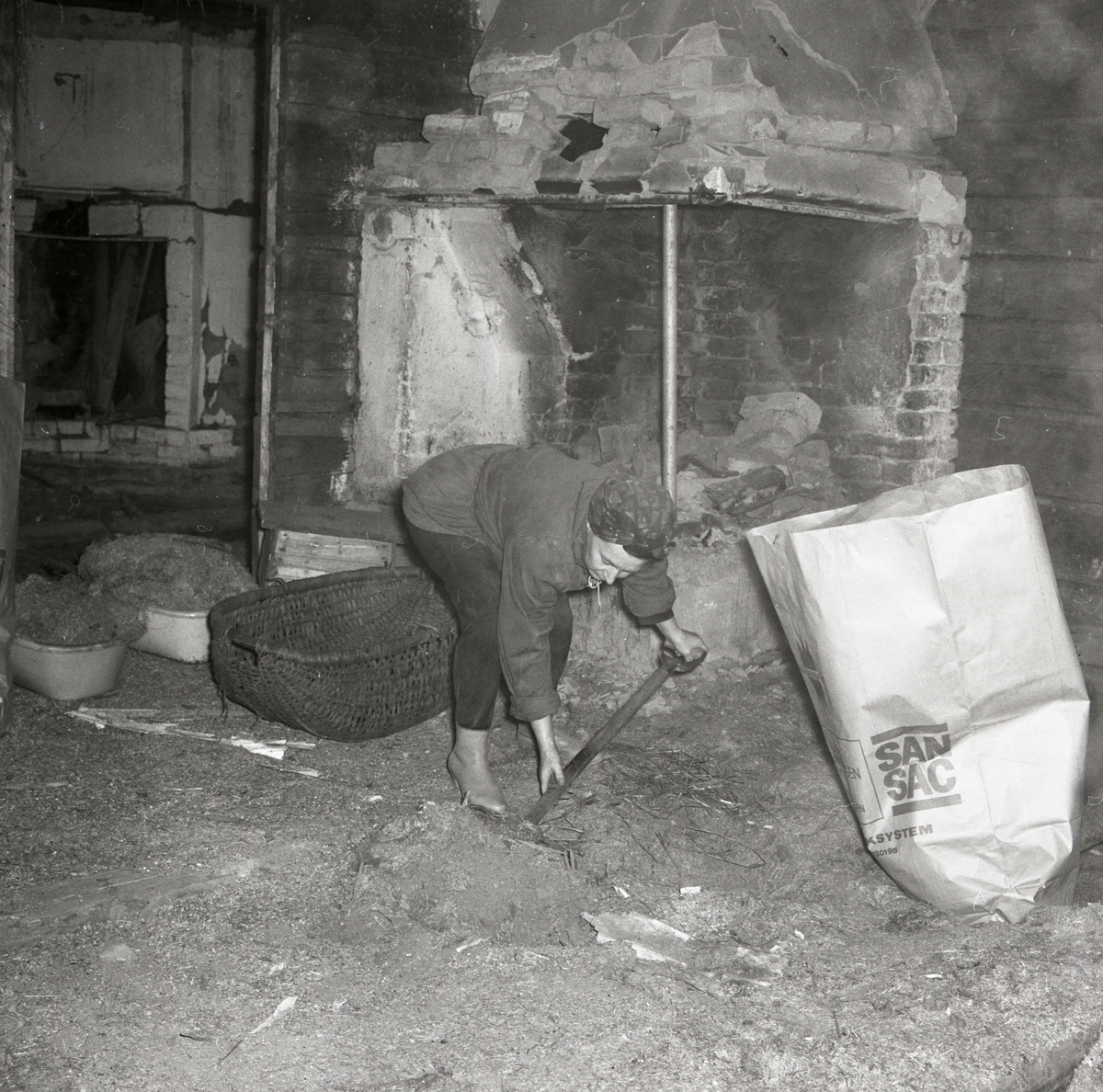 En kvinna plockar upp skräp vid rivningen av ett hus i Rengsjö, 1967.