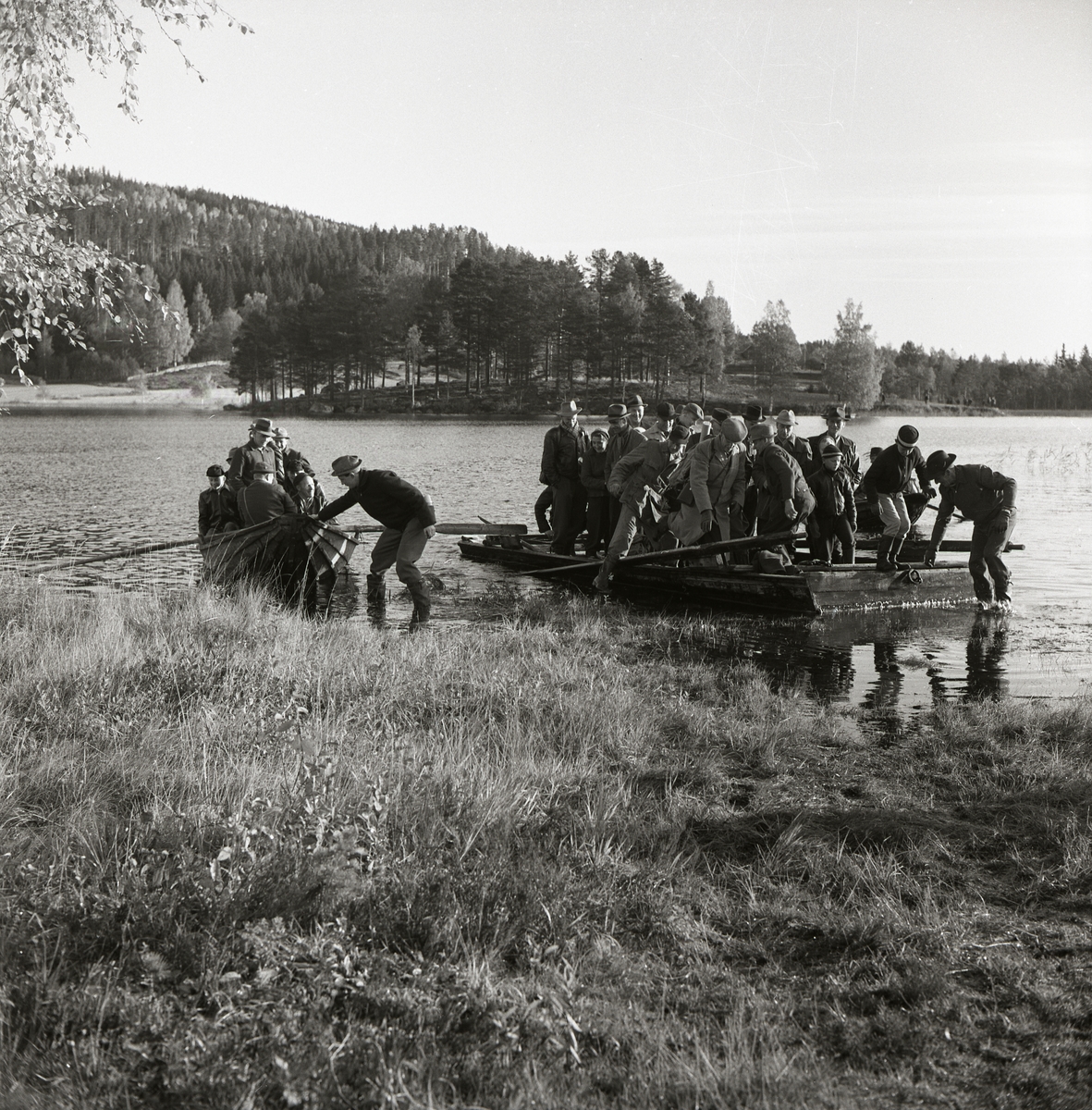 Några människor drar in en båt och en flotte till land vid sjön Stornien, 6 oktober 1957.