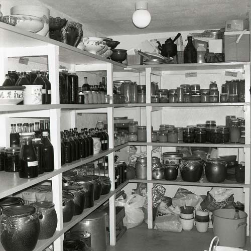 Ett skafferi vid gården Sunnanåker med bunkar, flaskor i hyllor, 1975.