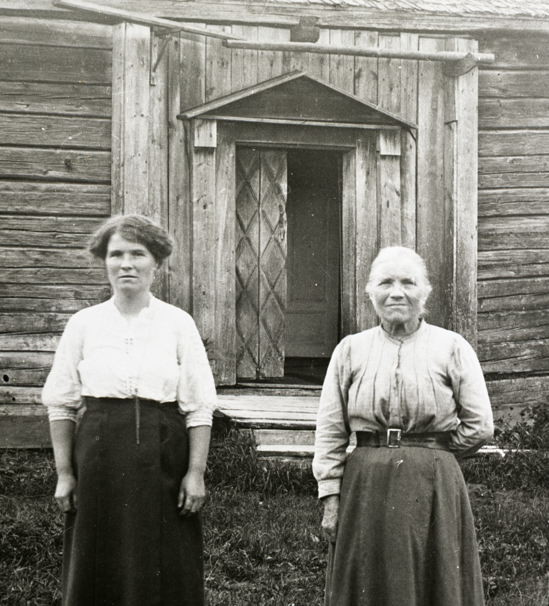 Två kvinnor står framför ingången till ett hus.