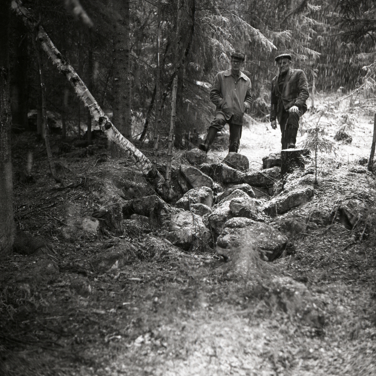 Två män står och beskådar ruiner i Västerby, 5 maj 1968 i Rengsjö.