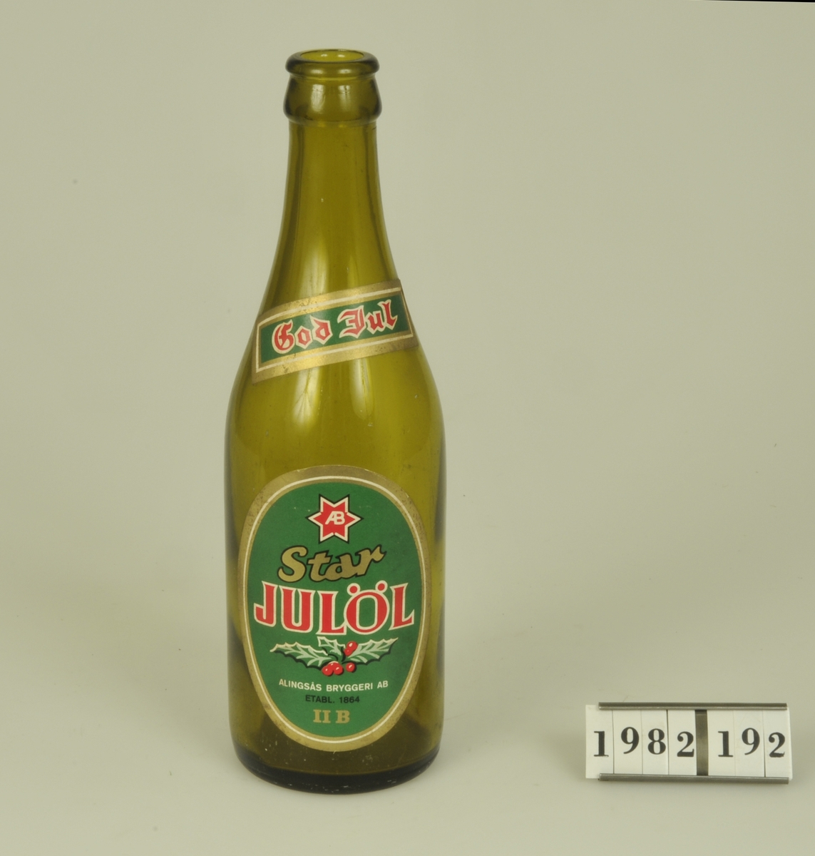 Av brunt glas.

Etikett med grön botten och röd och guldfärgad
text - "Star Julöl Alingsås Bryggeri AB. Etabl.
1864 II B".
