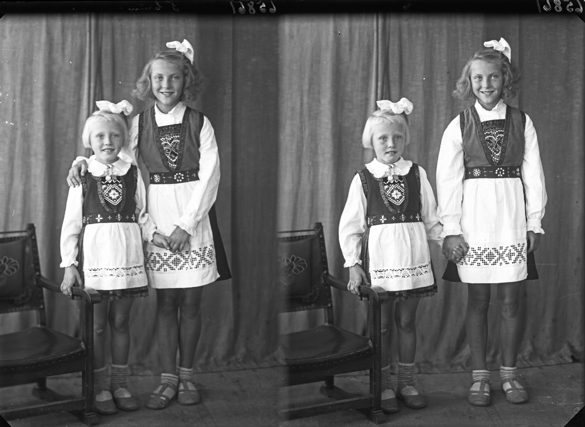 Gruppebilde. Familiegruppe på to. To unge piker i nasjonaldrakt med sløyfer i håret. Søstre. Bestilt av Erling Nilsen. Strangt. 181