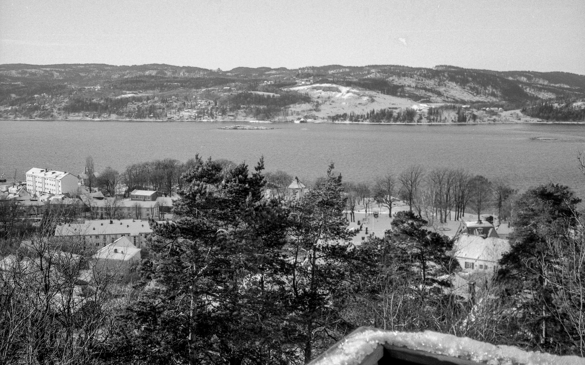 Utsiktsbilde over Frogn og Drøbak over Oslofjorde mot Hurumlandet. Vinterlandslap med småhusbebyggelse og blokker.