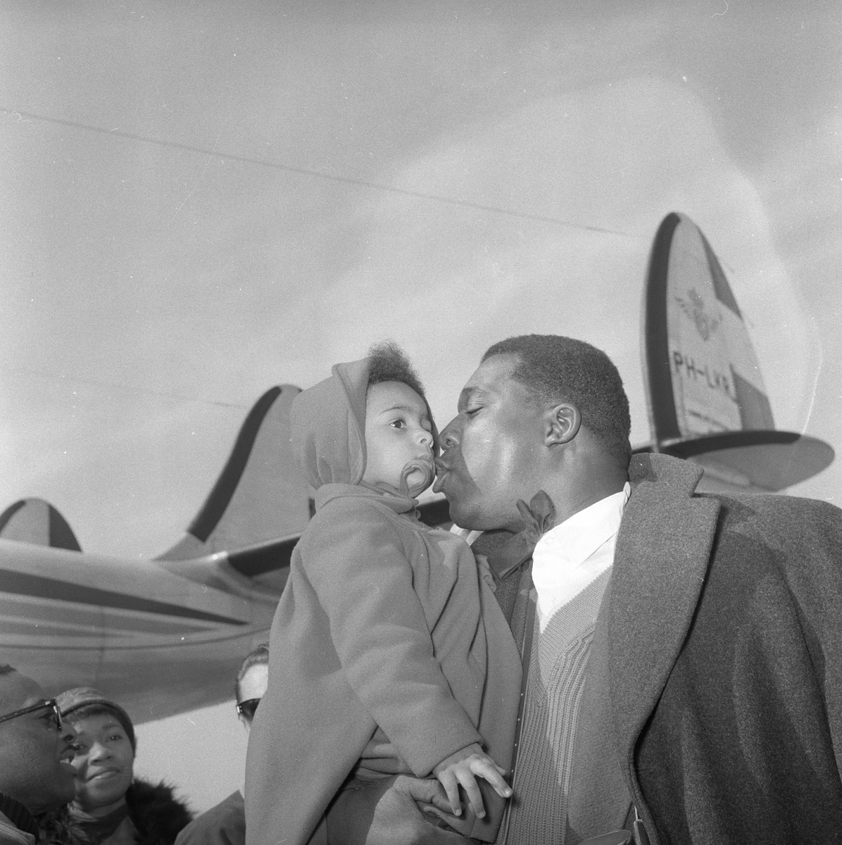 Sangere til oppsetning av "Porgy and Bess" på Folketeatret. John McCurry sammen med datteren, et fly i bakgrunn. Fotografert april 1956.