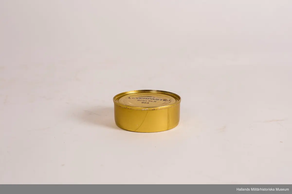 En konservburk som innehåller leverpastej. Burk av metall, guldfärgad. Svart text på lock och burk. Med deklaration.  Burken innehåller 70 g.