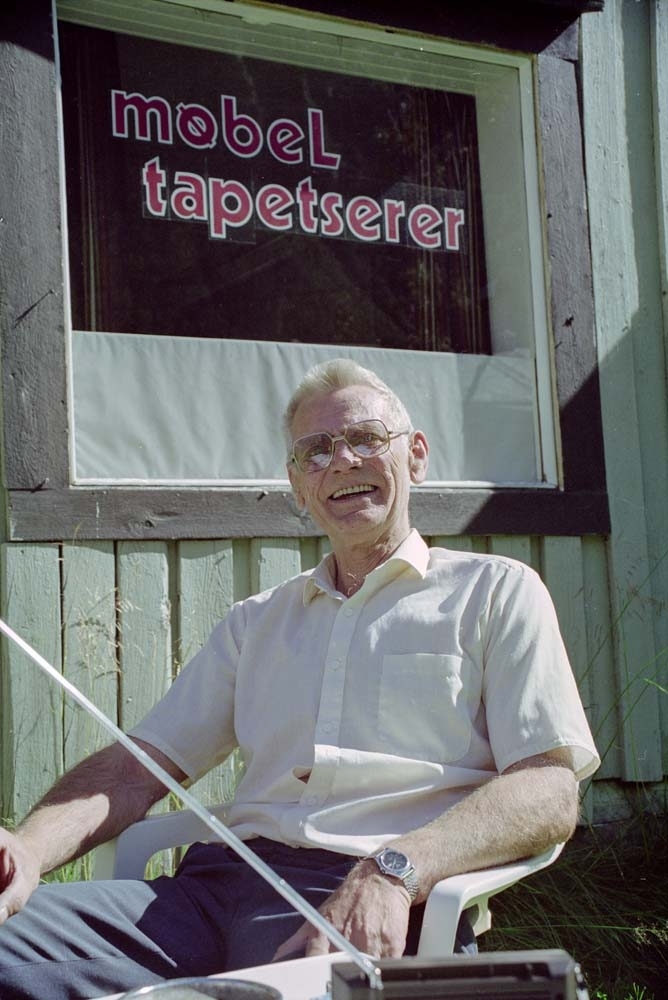 Møbeltapetserer Sverre Haustreis ved butikken med radio på bordet.