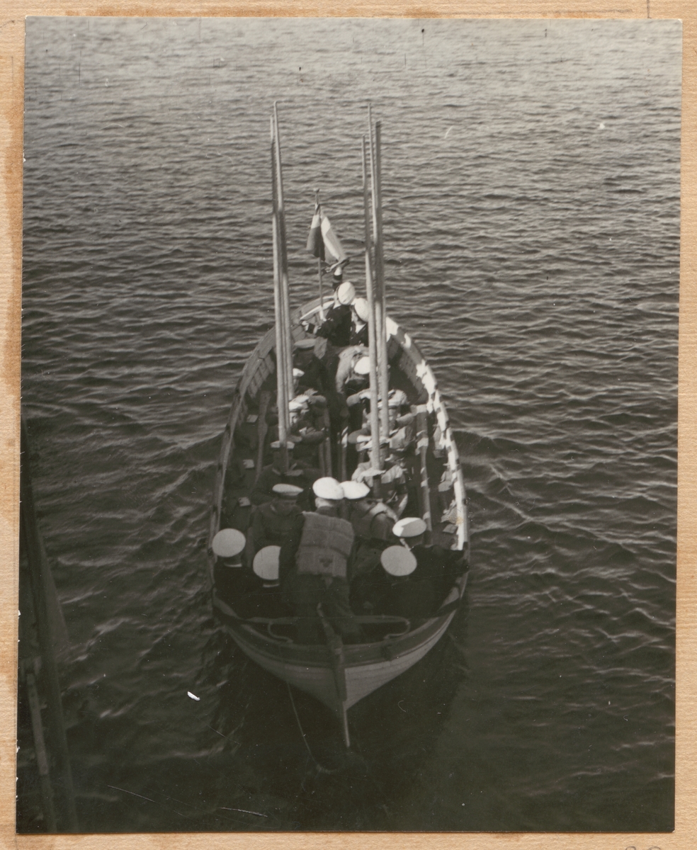 Bilden visar värnpliktiga i en roddbåt som håller årorna lodrätt upp i luften.