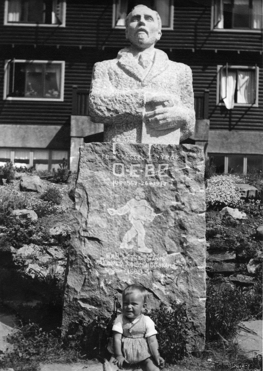 Byste av Ola Eriksson Bø, ved Valdres Folkehøgskule. Barnebarnet, Einar O. Bø sit ved steinen.