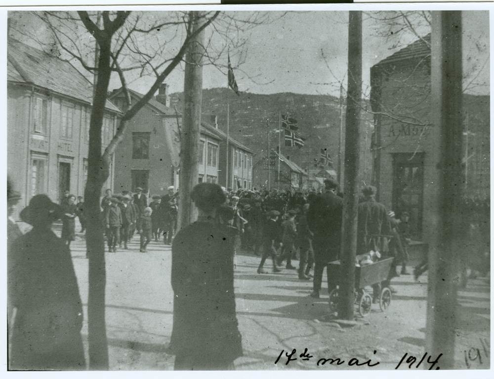 Folkemengde ved Nasjonaldagsfeiringen i 1914 i Mosjøen, med tog i Peter Bechs gate og oppover Strandgata.