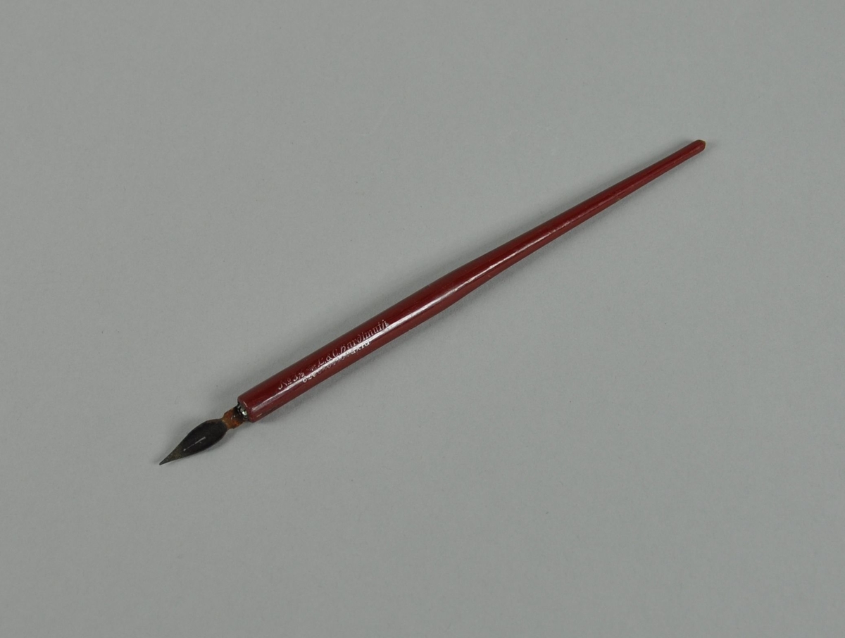 Penneskaft av rødmalt tre. Består av et dreid treskaft, sylindrisk nedre del, konisk øvre del, med innsatt holder for pennsplitt.