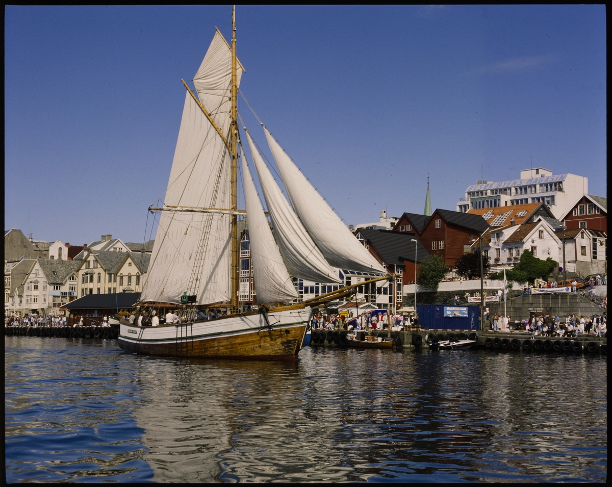 Hardangerjakta "Johanne Karine" har seilene oppe i Smedasundet i Haugesund. Det er tett med folk langs indre kai.