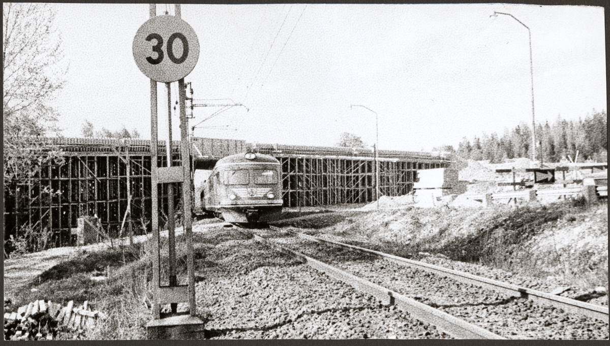 Viadukt byggs strax utanför Gusselby station. Ett Statens Järnvägar, SJ X9 motorvagnståg passerar byggarbetsplatsen.