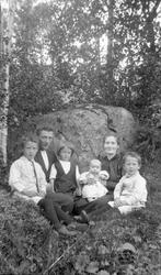 Portrett av familie sittende på gressmark.