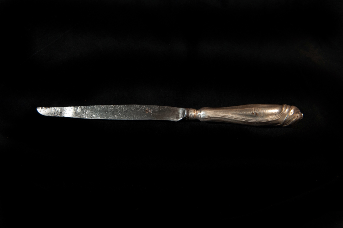 En spetsig kniv med skaft av silver i rokoko. Mycket otydliga stämplar. 
Tillverkad i Jönköping.