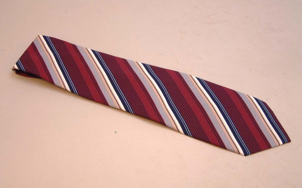 Diagonalrandig slips i färgerna vinrött, mörkblått, beige och grått.
Slipsen har kardborrband (säkerhetsslips).
