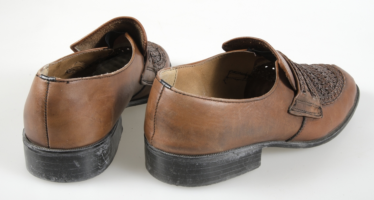 Ett par skor (loafers) av ljusbrunt läder med flätad överdel. Gummisulor. Maskinsydda. Söm vid tårna. Storlek 42. Lite räfflade klackar. Märkt: ANGLISA, OBERMATERIAL-LEDER.Samhörande med nr. UM 19115-19188.