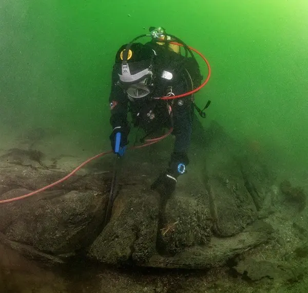 Dykker under vann sager i vrak på sjøbunnen: Arkeolog Elling Utvik Wammer sager ut skiver av hudbord til datering av skipsvraket ved Drengeholmen.. Foto/Photo