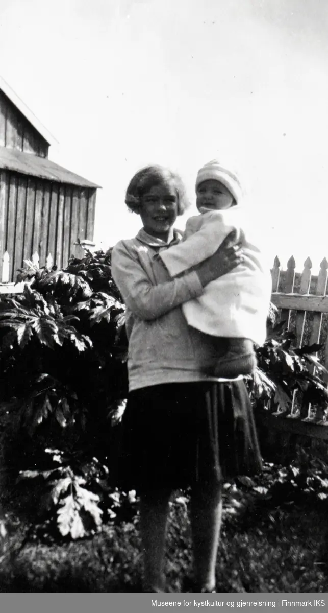 Nordvågen. Ragnhild Berg med broren Bjarne i hagen på Holmen. I bakgrunnen Tromsøpalme og vaskehuset. 1929.